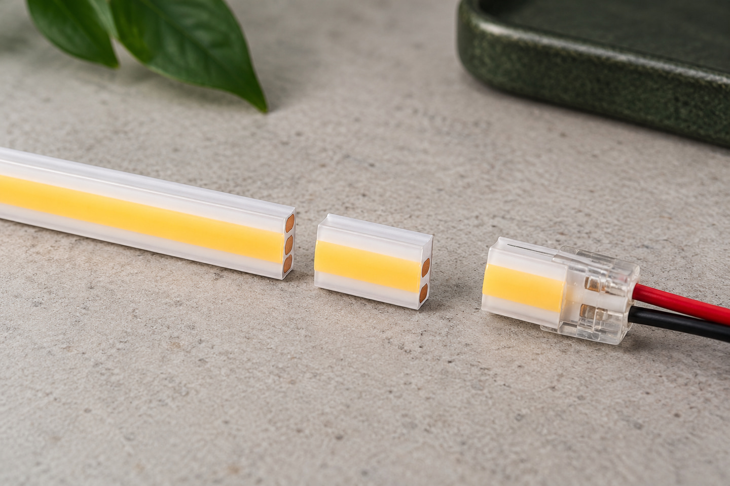Encapsulated LED strip, cut section and connector arranged separately on a workbench.