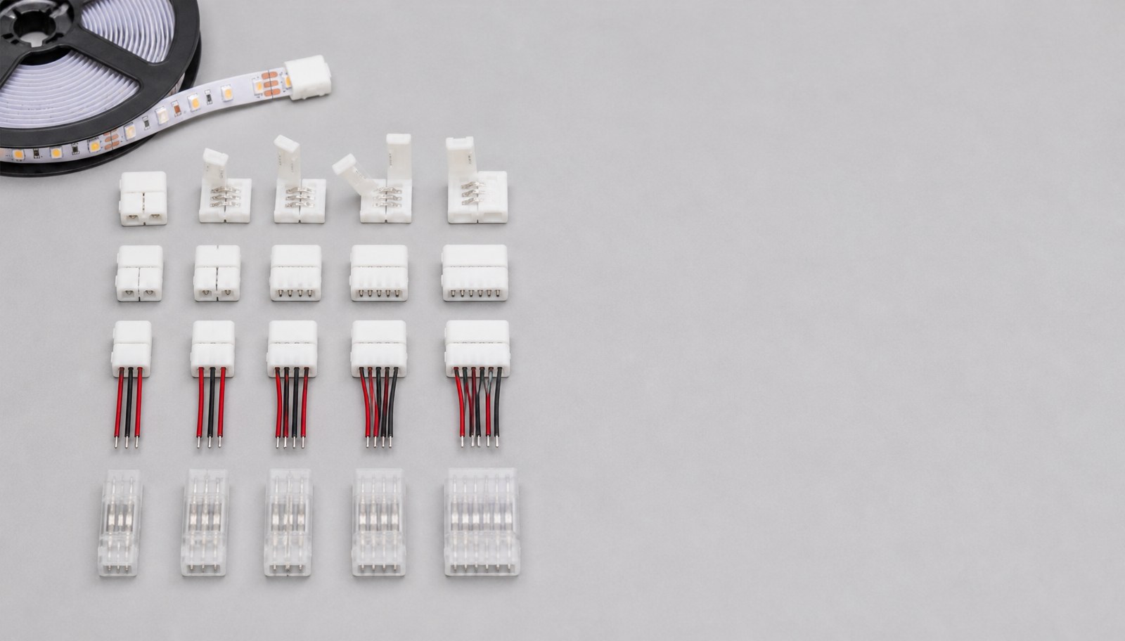 An organized flat-lay of assorted LED strip connectors arranged in rows on a gray studio surface.