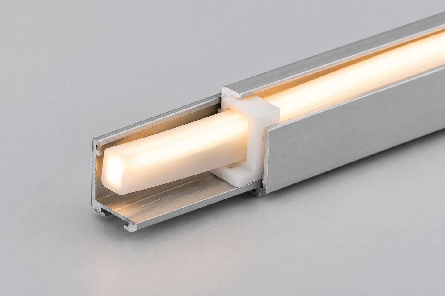 A close-up of illuminated neon flex seated inside an open aluminum mounting channel with a clip.