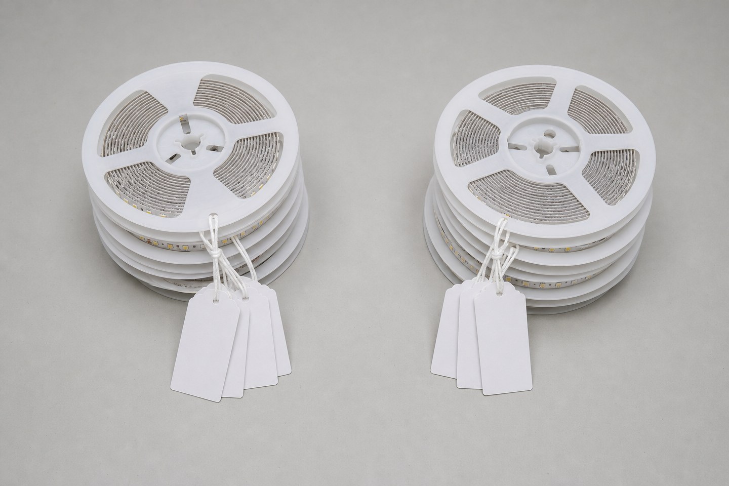 Two separate groups of LED strip reels with blank tags, grouped and separated on an inspection table.