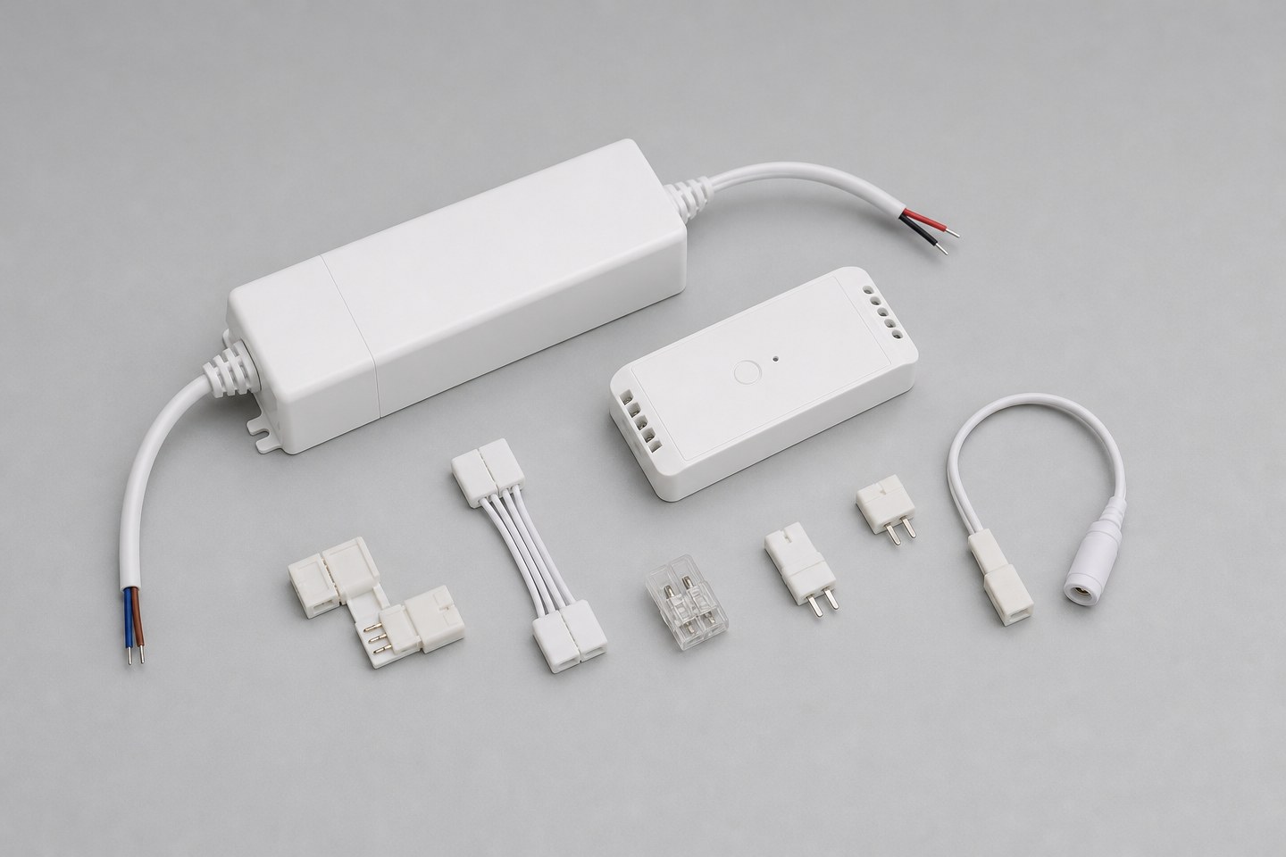 A small organized collection of LED strip accessories: a driver, a controller and connectors.