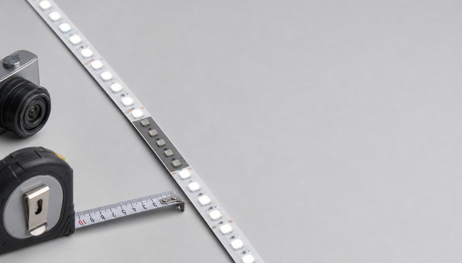 A close-up of an LED strip with one darker unlit segment among lit white LEDs, beside a measuring tape.