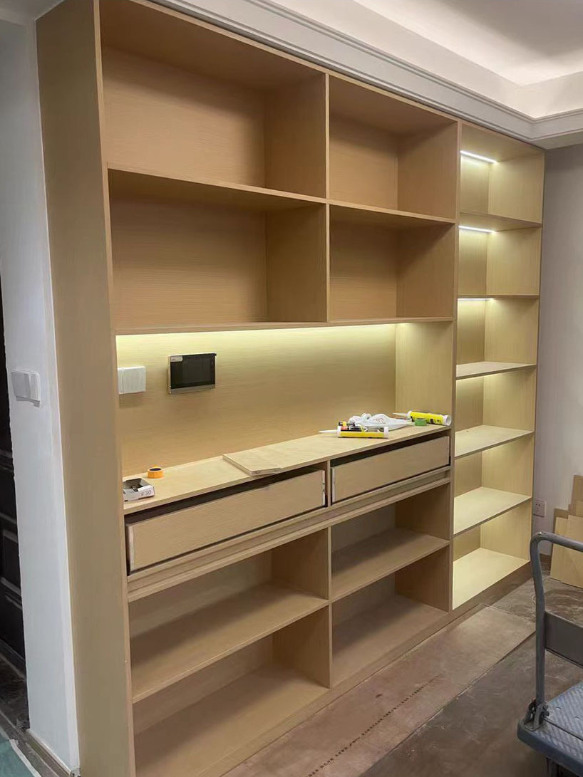 Linear lighting beneath shelves in a study cabinet.