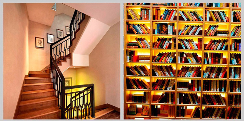 Warm-white strip lighting along stairs and library shelves.