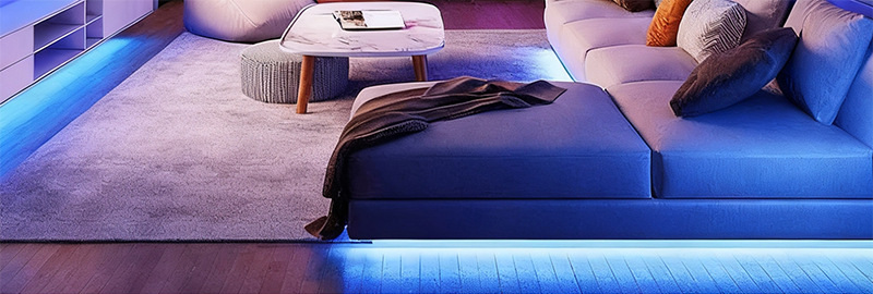 Blue strip lighting around the edge of living-room furniture.