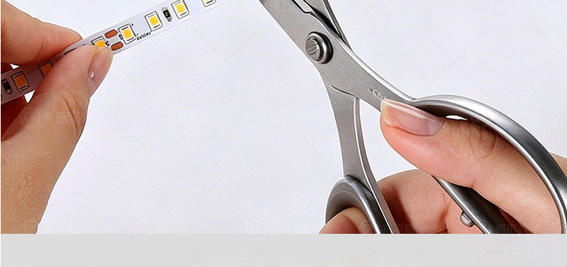 Scissors cutting a 2835 LED strip at a marked cut line