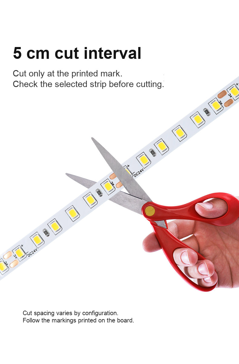 Scissors aligned with a marked cut point on a 24V LED strip
