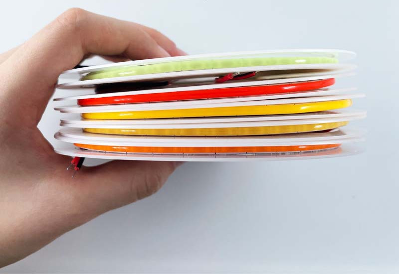 Hand holding several reels of ultra-narrow colored COB strip