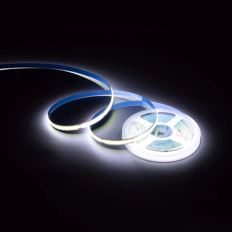 Cool-white COB LED strip glowing beside its reel